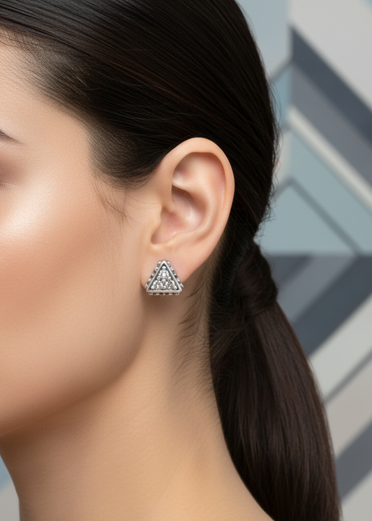 Close-up of a woman wearing a geometric triangle earring with a geometric patterned background.